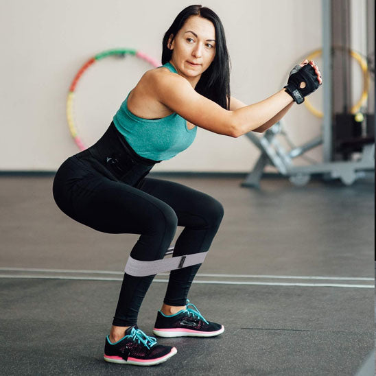 femme vue de cote et fait des squats avec un élastique